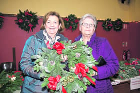 Rosaleen Briody and Ethel Ellis hold up a beautifully-crafted Christmas wreath at the Colmcille Christmas market, which took place recently. Photo: Michelle Ghee