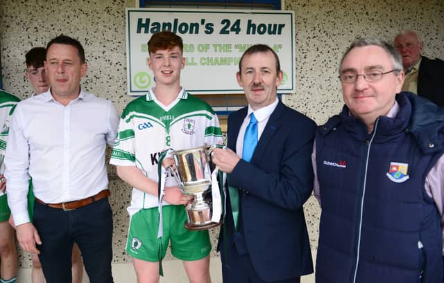 Niall Farrelly, the captain of the Killoe Og minor team, is presented with the Harte Cup by County Board Chairman Eamon Reilly with fellow officers Gerry Hagan and Finbarr Meehan also in the picture.