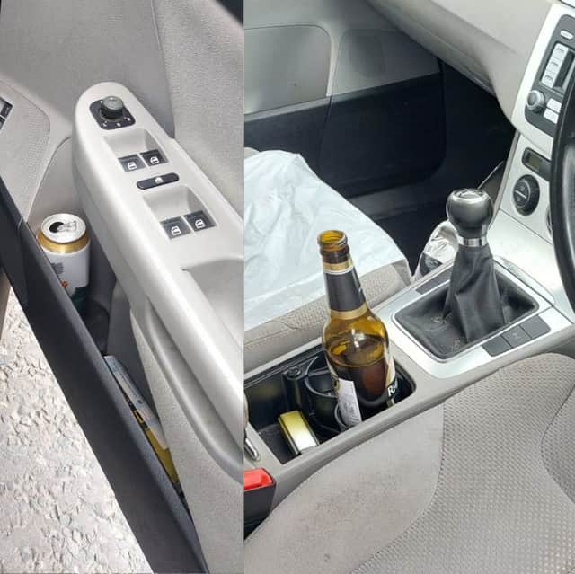 An open bottle of alcohol in the cup holder and an open can on the driver's side door