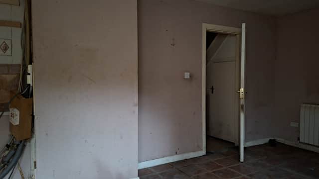 MAY 8 2026: The flooding that covered the kitchen floor at the time the house was boarded up has since been cleared. Scorch marks can be seen on the door. The rest of the house remains in darkness