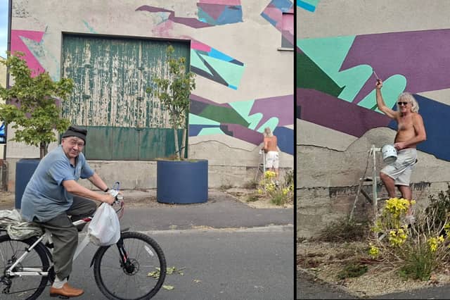 A local cycling by the mural as Brian Lyons carries out his work