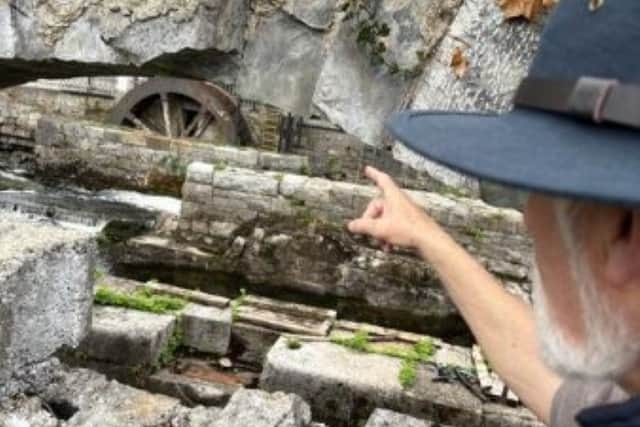 Original stone work that was in mill wheel area on crates with mill wheel axle in background