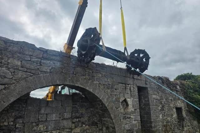 Mill wheel axle being hoisted out after it was uncovered in overgrowth during work which began on July 7