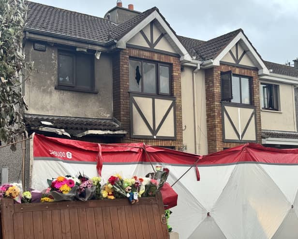 External view of a house showing signs of fire damage, with a forensic tent erected outside