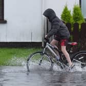 A boy riding a bike down a flooded street
