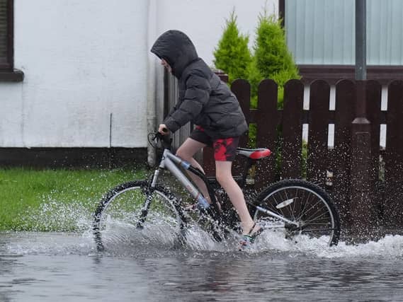 A boy riding a bike down a flooded street