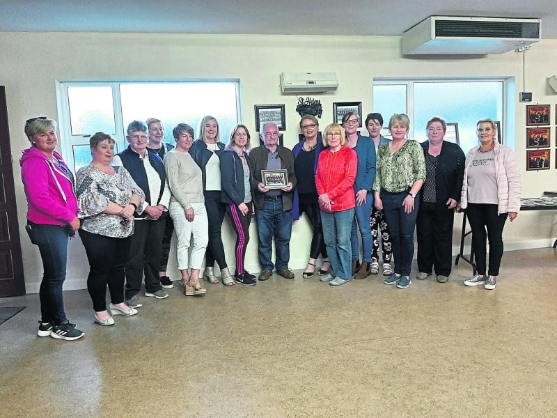 Liam Forde (centre) being presented with a photograph of himself and the current St Helen's ladies football senior panel, by some former members of St Helen's and Eire Og teams on a trip down memory l