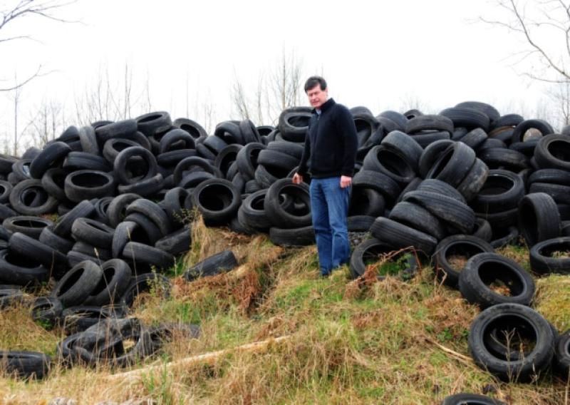 Councillor Sean Farrell pictured with the tyres which were dumped at Derrynagolia near Ballymahon last week. Photo: Declan Gilmore