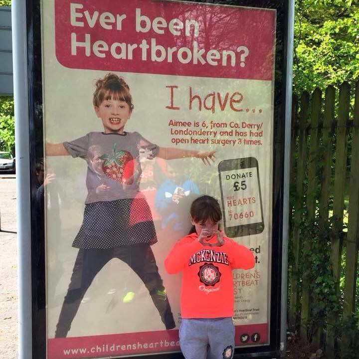 Aimee Brady in front of a Children's Heartbeat Trust billboard.